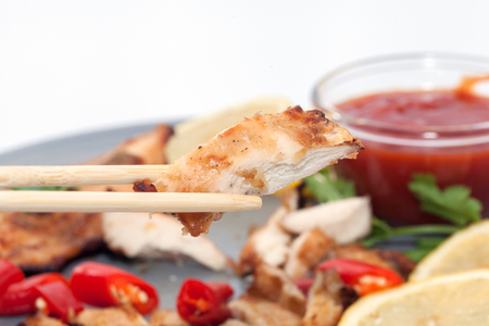close up of chopstick and chicken breast with sauceの写真素材