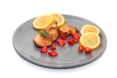 Roast chicken with chilli, lemon on grey plateの写真素材