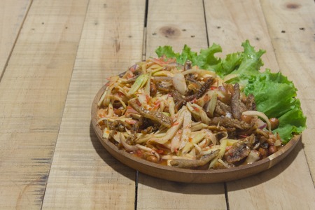spicy green mango salad on wooden plateの写真素材