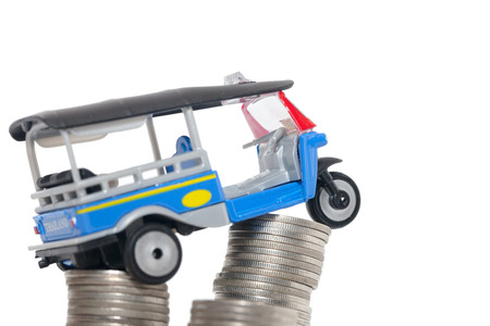 Thai traditional tuk tuk toy and coin on white backgroundの写真素材