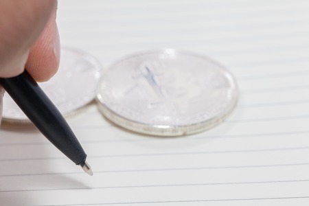 close up of hand writing on notebook and bitcoin, empty space