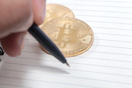 close up of hand writing on notebook and bitcoin, empty spaceの写真素材