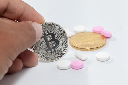 close up of bitcoin and pill on white backgroundの写真素材