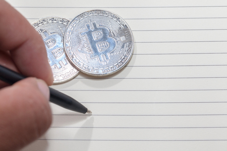 close up of hand writing on notebook and bitcoin, empty spaceの写真素材