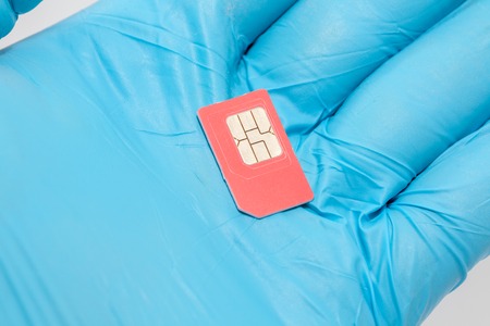 hand in blue glove holding sim card on white backgroundの写真素材