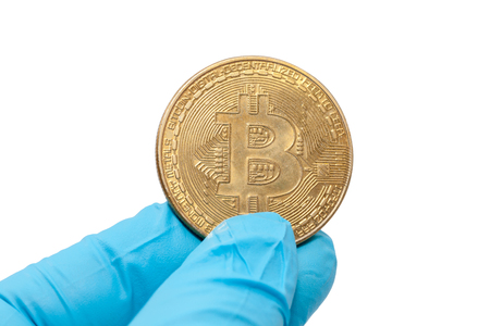hand in blue glove holding bitcoin on white backgroundの写真素材