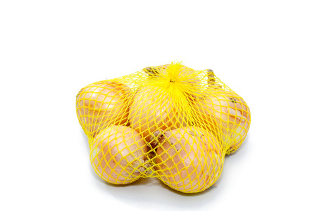 Fresh onions in a yellow plastic netの写真素材