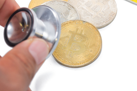 Doctor hand hold stethoscope check gold bitcoin on white backgroundの写真素材