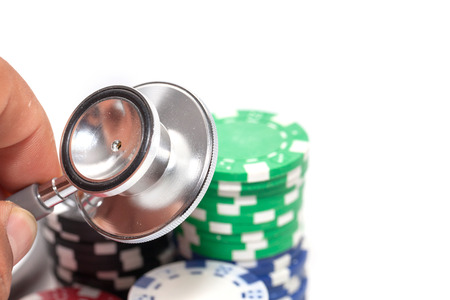 stethoscope and pile of casino chips on white background