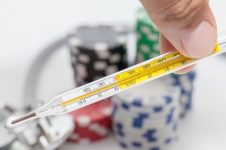 Thermometer and pile of casino chips on white background