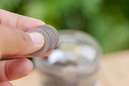 hand holding coin with glass jar ,savings and financial investment concept idea