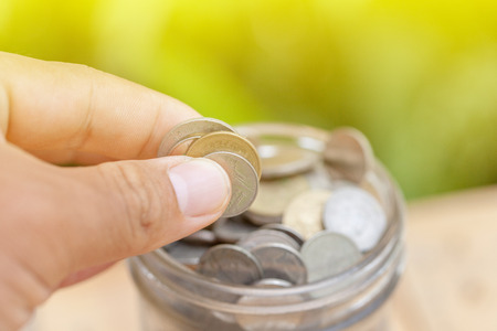 hand holding coin with glass jar ,savings and financial investment concept idea