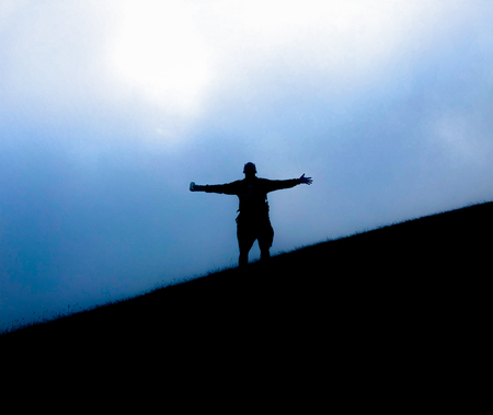 silhouette of tourist hiker acting on top of mountain