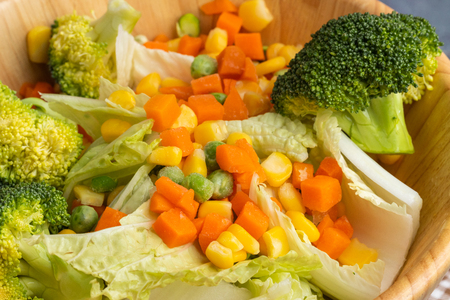 carrots corns broccoli and peas on wooden bowlの写真素材