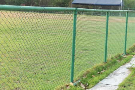 green metal fence at grass football fieldの写真素材