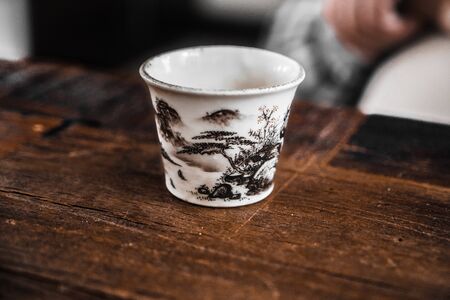 Cup on a wooden table. Ceramic cup for Chinese tea ceremony. A cup for Chinese tea. Hand painted chinese cupの写真素材