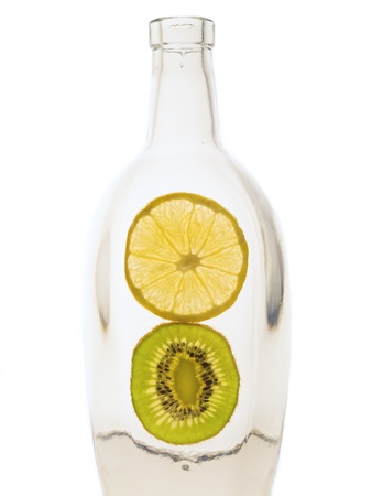 Bottle with cut lemon and kiwi fruit on white backgroundの写真素材