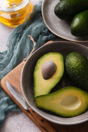Two slices of avocado on gray bowl with fresh avocado on gray background.の写真素材