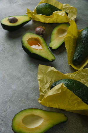 Slices of avocado on green table wrapped in yellow paper.の写真素材