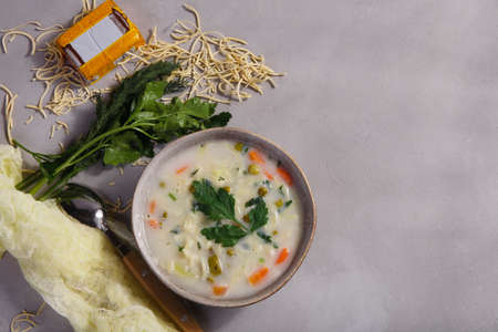 Melted cheese soup with green peas and noodle with fresh greens on gray background, copy spaceの写真素材