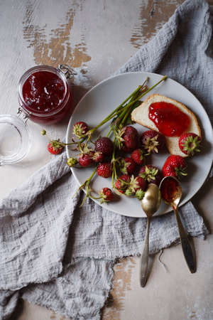 Summer breakfast concept with srawberry jam with bread and fresh harvested berries on gray plate.の写真素材
