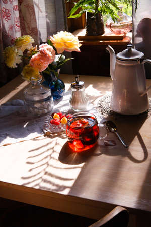A white table with a cup of tea in the early summer morning.の写真素材