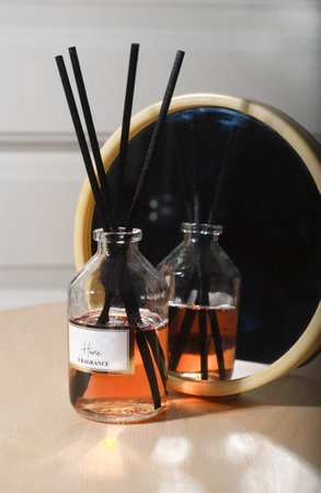 Aroma reed diffuser on wooden table in home interior with a round mirror.の写真素材