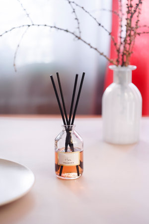 Aroma reed diffuser on white table with white vase and red curtains.の写真素材