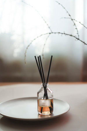 Aroma reed diffuser on plate on white table in bed room interior.の写真素材