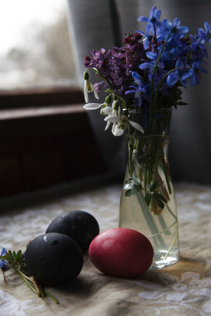 Snow drops, fumewort and scilla flowers in glass vase with painted red eggs on rustic table, Easter selebration concept.の写真素材