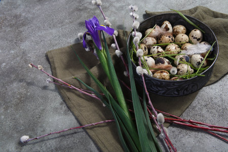 Quail eggs in metal rustic bowl with willow branches and iris flower, Easter decor concept with copyspace, selective focus.の写真素材
