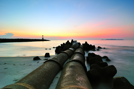 Sunrise at the beach near a lighthouseの写真素材