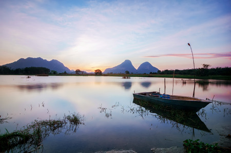 Lonely boat by the lakeside during beautiful sunsetの写真素材