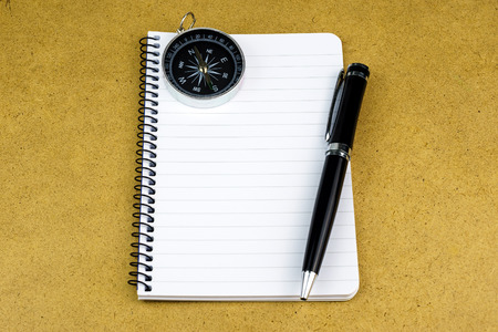 Blank notepad with pen and compass on wooden backgroundの写真素材