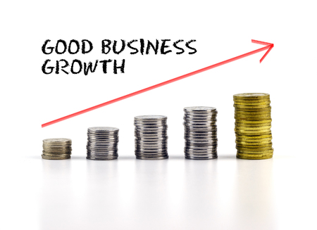 Conceptual image. Stacks of coins against white background with red arrow and GOOD BUSINESS GROWTH words.の写真素材
