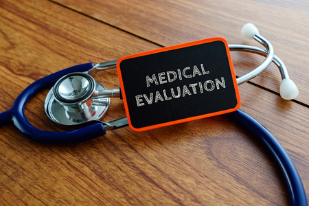 Medical concept.Word MEDICAL EVALUATION with stethoscope on wooden table.の写真素材