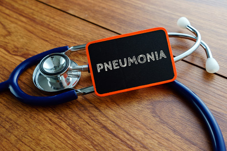 Medical concept.Word PNEUMONIA with stethoscope on wooden table.の写真素材