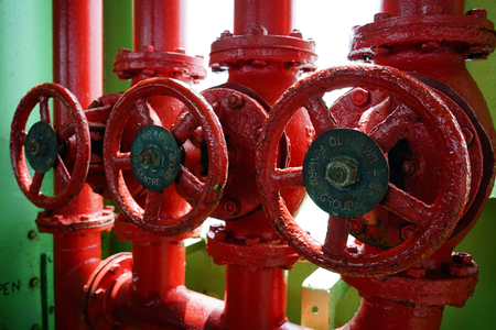 Old valves and pipes painted in vivid bright red color.の写真素材
