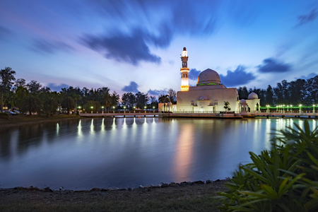 Beautiful white mosque by the lakeside during sunrise with reflection on the lake in Terengganu, Malaysia.の写真素材