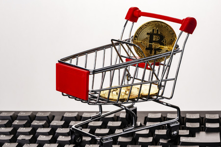 Golden bitcoin cryptocurrency in a shopping cart on top of computer keyboardの写真素材