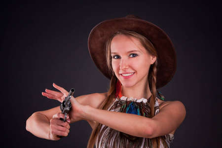 The American Indian girl in a cowboy's hat holds a pistolの写真素材