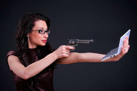 Business woman with a computer and a pistol in handsの写真素材