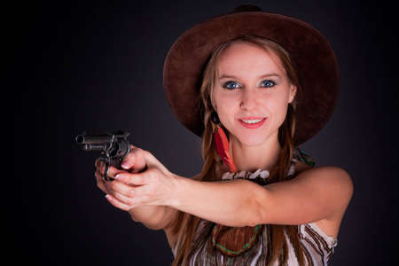 The American Indian girl in a cowboy's hat holds a pistolの写真素材