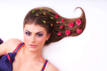 Pretty girl lying with flowers-roses in her hairの写真素材