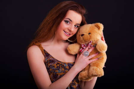 Beautiful longhair girl is holding the teddy bearの写真素材