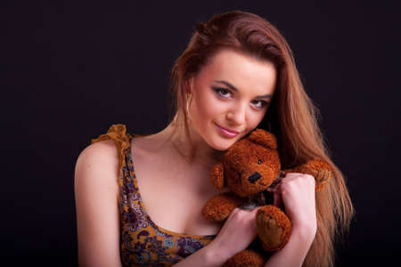 Beautiful longhair girl is holding the teddy bearの写真素材