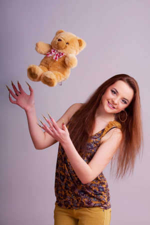 Beautiful young longhair brunette playing with bearの写真素材