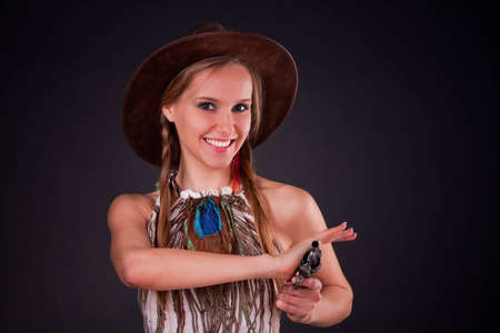 The American Indian girl in a cowboy's hat holds a pistolの写真素材
