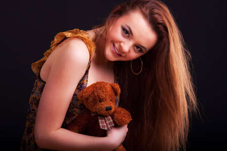 Beautiful longhair girl is holding the teddy bearの写真素材