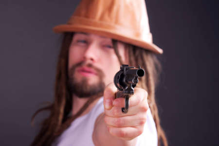 Dour guy wearing a hat holding a gunの写真素材